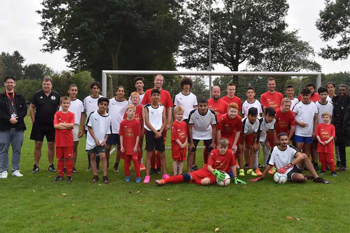 Spieler aus unterschiedlichen Hintergründen spielen gemeinsam Fußball - Inklusive Sportgemeinschaft
