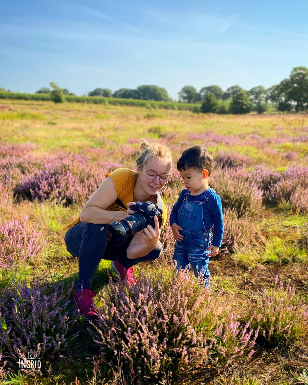 Ingrid de fotograaf laat haar fotos zien aan jongetje tijdens een fotoshoot op de paarse heide
