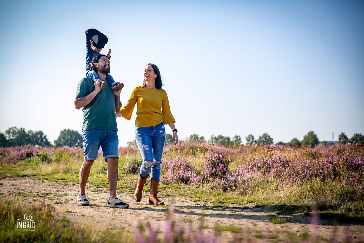 Kindje zit op de schouders van papa en pakt zijn pet af