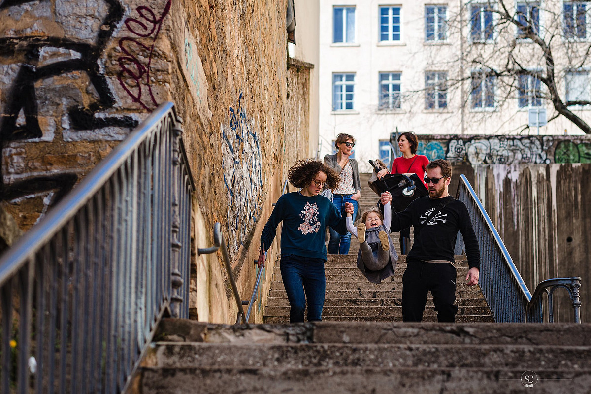 Famille descend les marches colorées de la Croix-Rousse lors d'une séance photo à Lyon