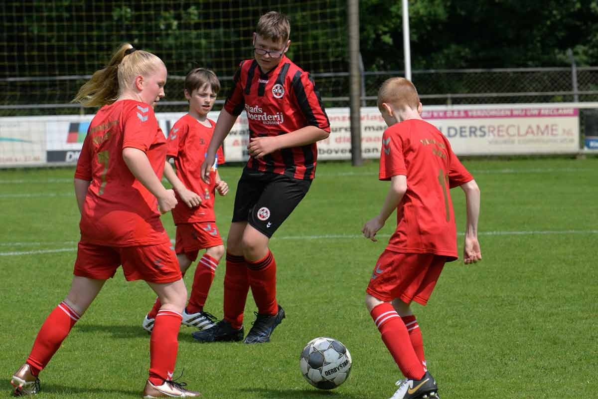 Kinder und Erwachsene spielen gemeinsam Fußball bei sonnigem Wetter