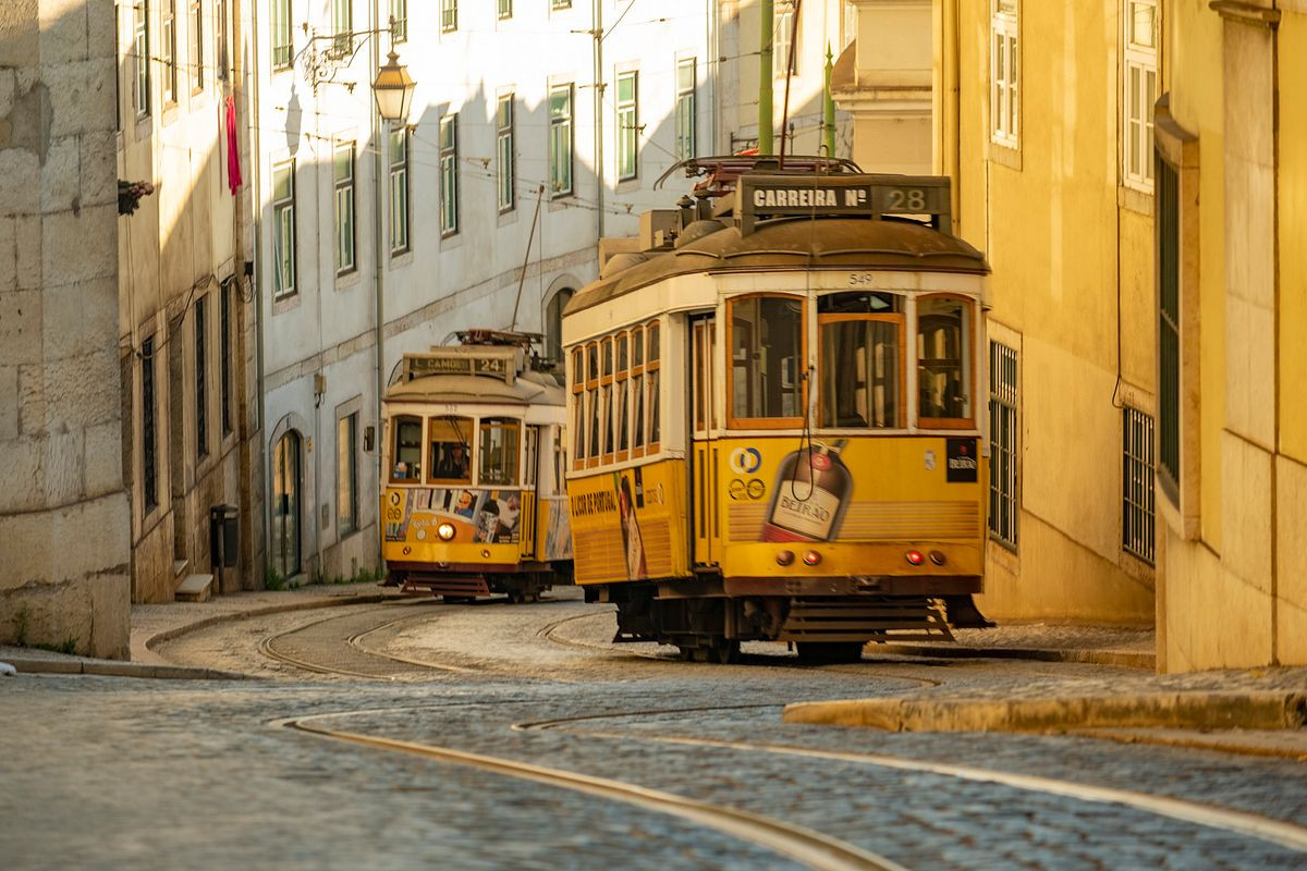 Two trams pass in a narrow Lisbon street