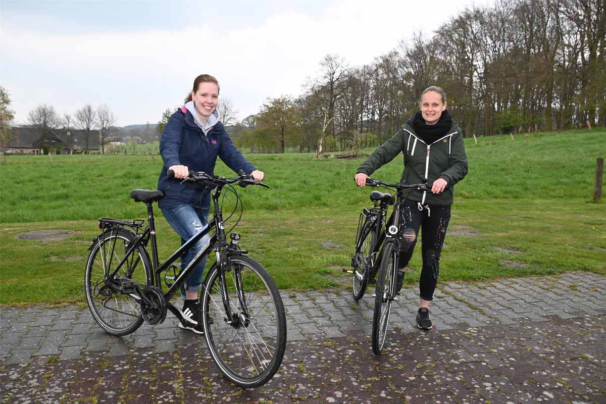 Zwei junge Frauen mit Fahrrädern, die sich auf eine Radrundreise begeben.