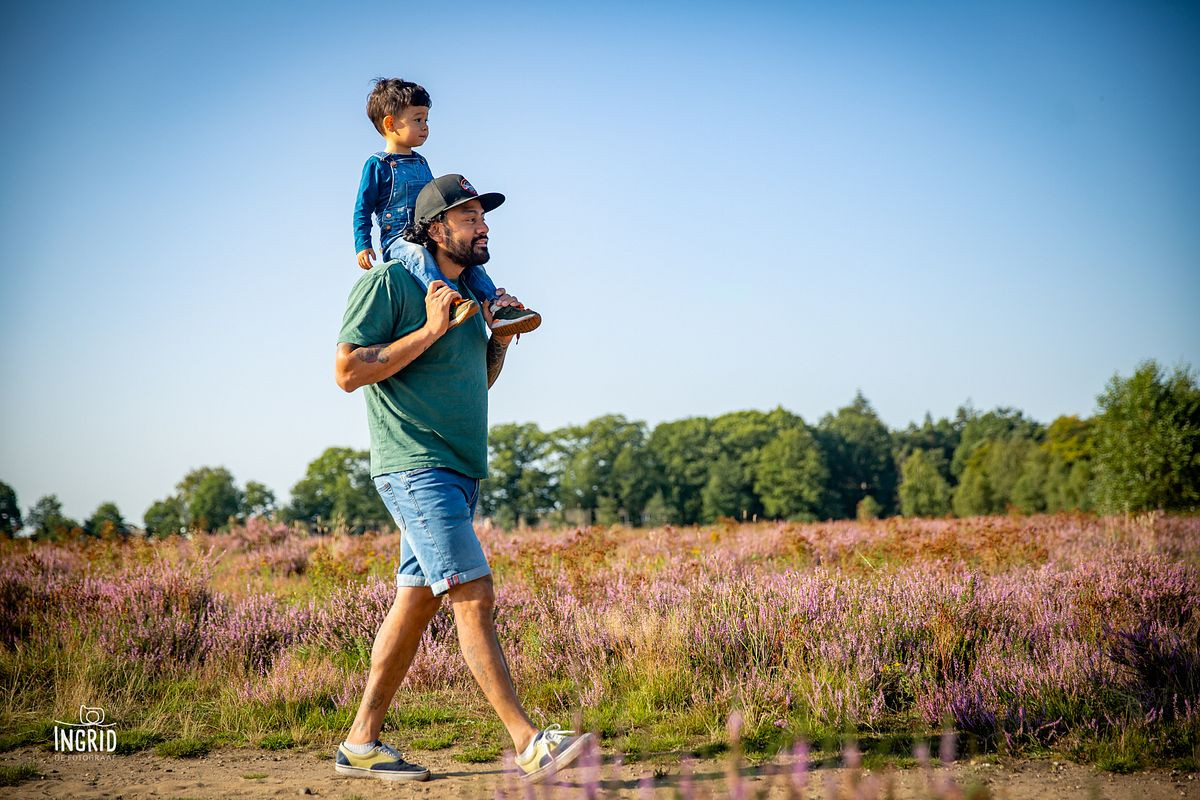 Kindje zit bij papa op de schouders