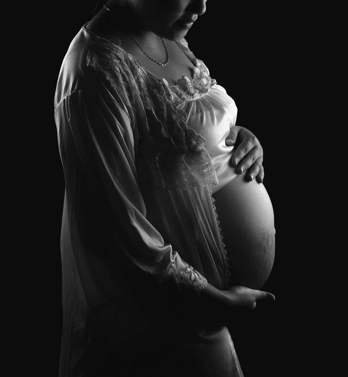 Maternity photoshoot in black and white with mother holding tummy.