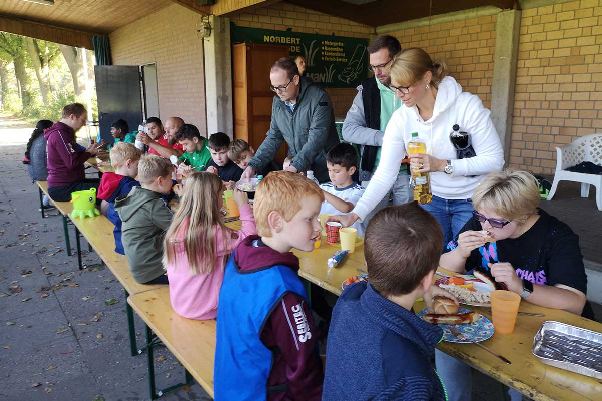 Spieler und Eltern genießen gesellige Momente bei Bratwurst und Limonade.